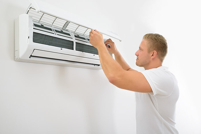 man inspecting air conditioning unit for problems